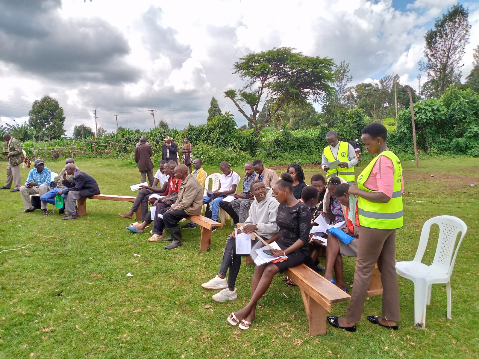 Facilitator wearing a reflective vest speaking to seated students during an outdoor Emgwen TVC career awareness briefing.